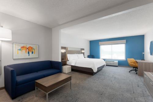 a hotel room with a bed and a blue couch at Holiday Inn Express Hotel & Suites Huntsville West - Research Park by IHG in Huntsville