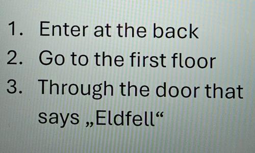 a text box with the words enter at the back and go to the first floor at Central Apartments in Vestmannaeyjar