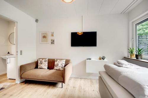 a bedroom with a couch and a tv and a bed at Billund HomeStay in Billund