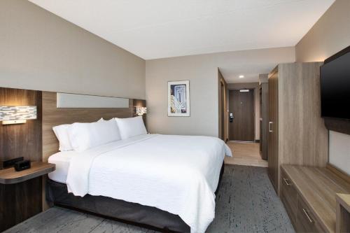 a hotel room with a large bed and a flat screen tv at Holiday Inn Express Sault Ste Marie by IHG in Sault Ste. Marie