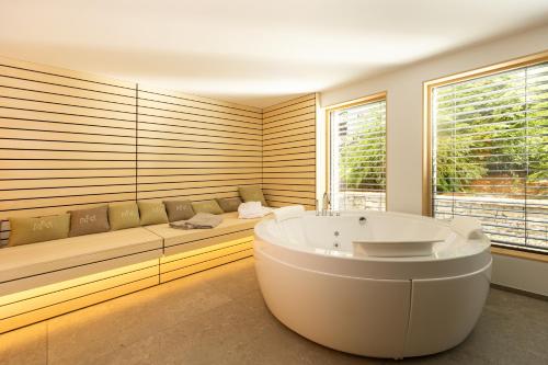 un bagno con vasca e divano di Chalet Bohinj Bliss Wellness and view of Triglav a Bohinj