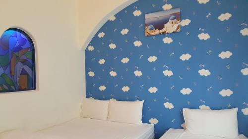 a bedroom with a blue wall with clouds at Rainbow B&B in Dahan