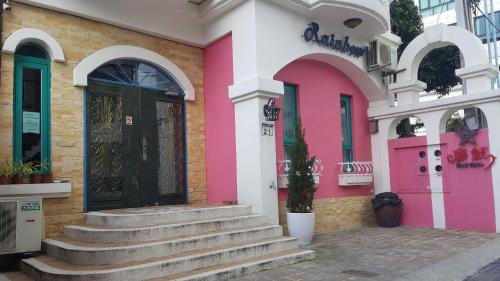 a pink and white building with a door and stairs at Rainbow B&B in Dahan