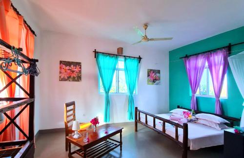 a bedroom with a bed and a table and windows at Frangipani House Nungwi Zanzibar in Nungwi