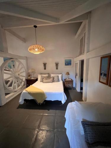 a bedroom with a white bed and a chandelier at Vila alecrim Guest House in Búzios