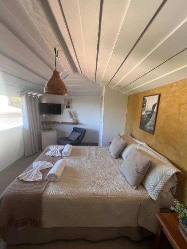a bedroom with a large bed with towels on it at Vila alecrim Guest House in Búzios