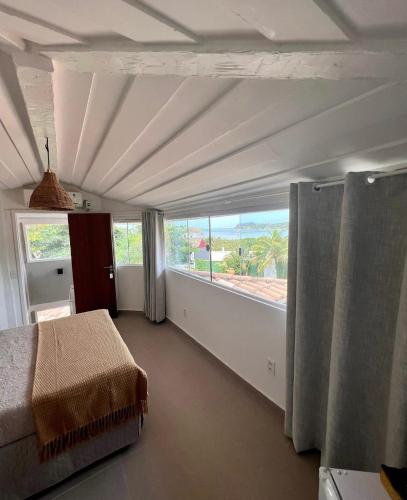 a bedroom with a bed and a large window at Vila alecrim Guest House in Búzios