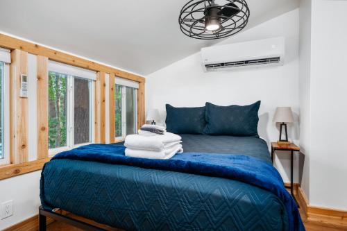 a bedroom with a blue bed with towels on it at Arbutus Lakeside Stay-Pontoon Rentals-Near TC! in Traverse City
