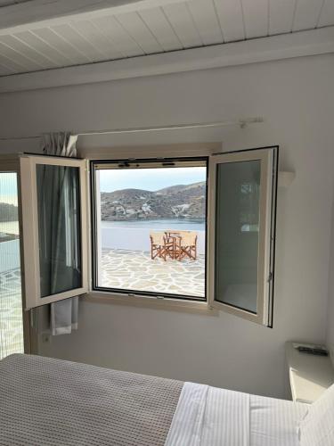 a bedroom with a bed and a window with a table at Heliopetra Punta in Ios Chora