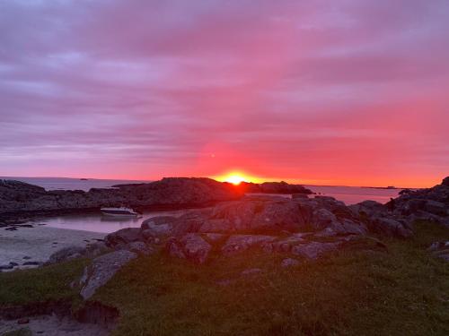 a sunset over the ocean with a boat on the shore at Flott Leilighet, 1 etasje med nydelig sjøutsikt in Karmøy