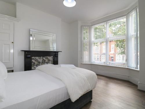 a white bedroom with a large bed and windows at 2 Evington Road in Leicester