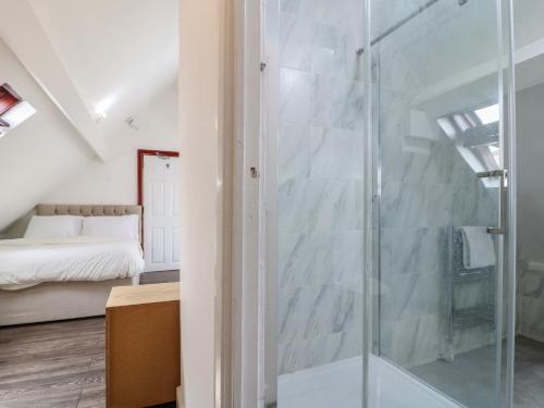 a glass shower in a bedroom with a bed at 2 Evington Road in Leicester