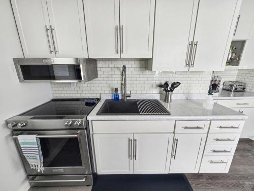 a kitchen with white cabinets and a sink at AWave From It All lakefront on Big Spirit Lake in Orleans