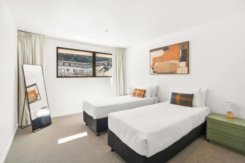 a hotel room with two beds and a mirror at Central on Shotover 2 in Queenstown