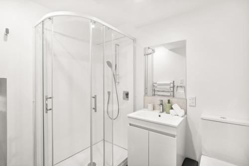 a white bathroom with a shower and a sink at Central on Shotover 2 in Queenstown