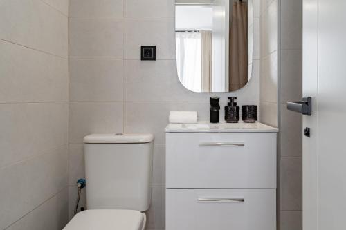 een witte badkamer met een toilet en een spiegel bij Light Brisa Apartment in Fuengirola