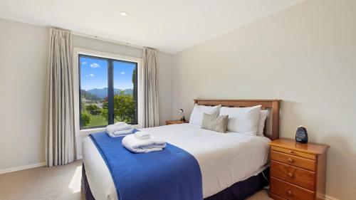 a bedroom with a large bed with towels on it at Warm and spacious 2 bedroom, downstairs apartment in Wanaka