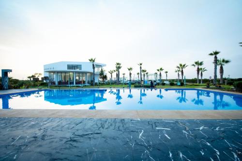 a large swimming pool with palm trees and a building at Garden Bay Appart'Hôtel in Casablanca