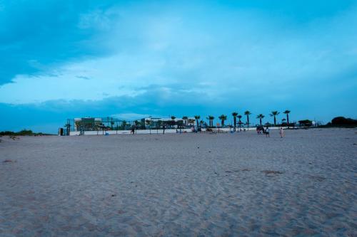 a beach with palm trees and people on the sand at Garden Bay Appart'Hôtel in Casablanca