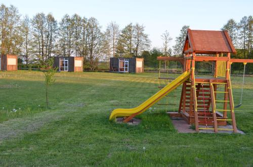 a playground with a yellow slide in a field at SaulesKempings in Mērsrags
