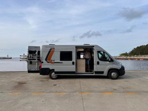 a white camper van parked next to a body of water at Kamper na urlop in Mrzeżyno