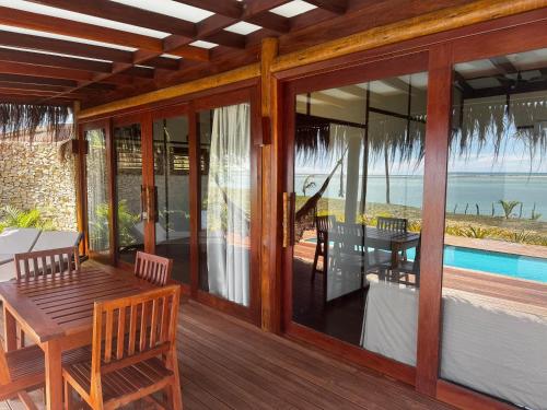 a screened porch with a table and a view of the ocean at Soledade Bangalôs - Kauli Seadi in Macau