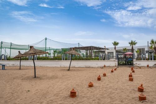 a sandy beach with umbrellas in the sand at Garden Bay Appart'Hôtel in Casablanca