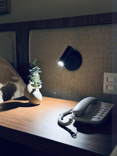 a telephone on a table with a vase and a lamp at Café Palace Hotel in Três Pontas