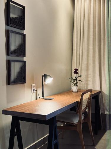 a wooden desk with a lamp and a chair at Café Palace Hotel in Três Pontas