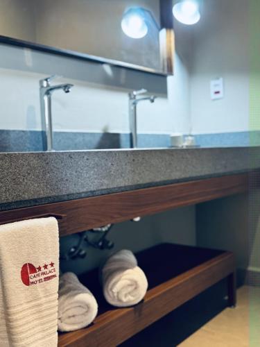 a bathroom with towels on a shelf under a sink at Café Palace Hotel in Três Pontas