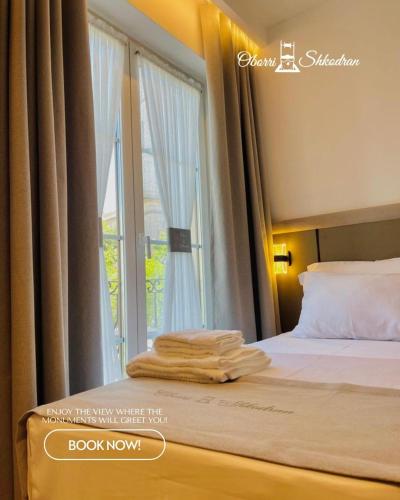 a bedroom with a bed and a window with curtains at Oborri Shkodran Boutique Hotel in Shkodër