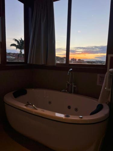 a bath tub in a bathroom with two windows at Café Palace Hotel in Três Pontas