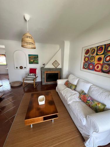 a living room with a white couch and a table at Casa do Algarvito in Terrugem