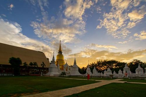 een uitzicht op een tempel met een zonsondergang op de achtergrond bij Chiangmai Tree Hostel in Chiang Mai