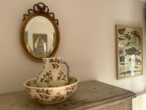 a vase sitting on a table in front of a mirror at Halte dans le Perche 