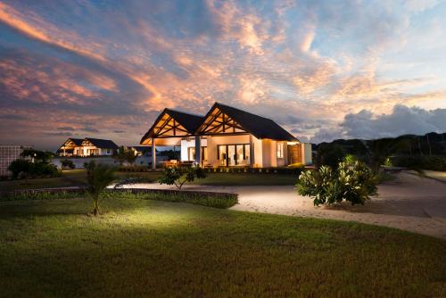 a large house with a sunset in the background at Mequfi Beach Resort in Mecúfi