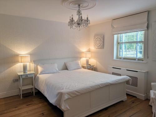 a bedroom with a white bed and a chandelier at Lady Hill, Royal Hillsborough in Hillsborough