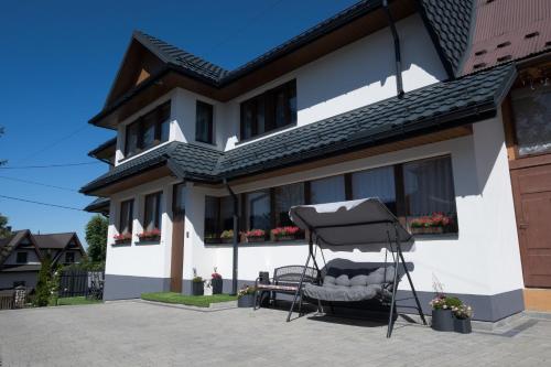 a house with a chair in front of it at Apartament przy Wyciągu z jacuzzi in Bukowina Tatrzańska