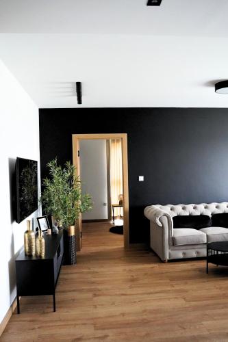 a living room with a white couch and a black wall at Apartamenty STUDIO in Busko-Zdrój