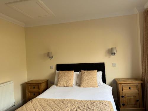 a bedroom with a white bed with two nightstands and two pillows at The Waverley Inn in Dingwall
