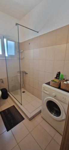 a washing machine in a bathroom with a shower at Grey House in Prinos
