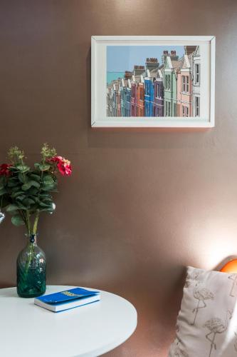 a vase of flowers on a table with a picture on the wall at Tiny House with Parking & Patio by Cool Bloo in Brighton & Hove