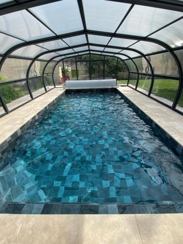 an indoor swimming pool with a glass roof and blue tiles at maison au calme avec piscine chauffée in Bucy-le-Long