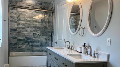 un bagno con due lavandini, una vasca e due specchi di Pet-Friendly Pool Bayside Coastal Cottage a Town Bank