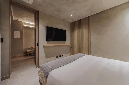a bedroom with a bed and a tv on the wall at Kuuna Luxury Stays by Wynwood House in Medellín