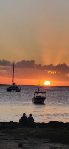 two people sitting on the beach watching the sunset at Play - Swim - Dive - Relax - Seaside Recharge in Cap Malheureux