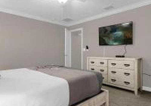 a bedroom with a bed and a dresser with a tv at 4243 PA - Storey Lake Escape 4BR Pool Home Near Disney in Kissimmee