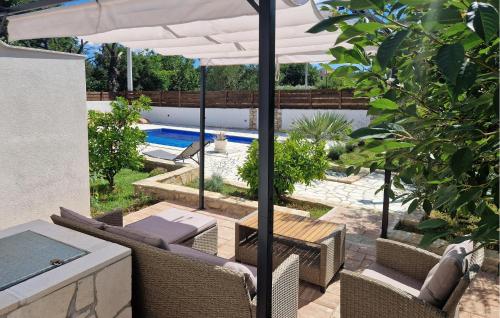 スコシャンにある3 Bedroom Cozy Home In Sukosanのパティオ(パラソル、椅子付)、プールが備わります。