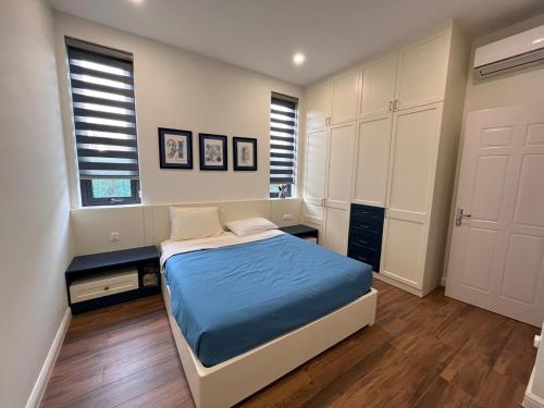 a bedroom with a bed and two windows at Nhà Hanha in Kon Rung (1)