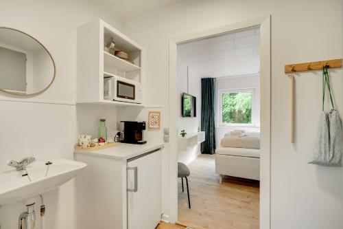 a white bathroom with a sink and a bedroom at Billund HomeStay in Billund